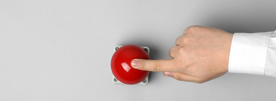 Human hand pushing a red button, representing stress response at work and emotional triggers