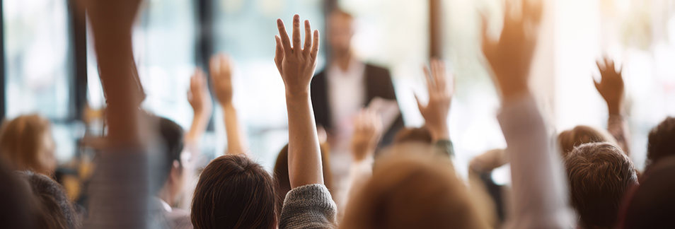 people raising their hands as the leader makes meetings more engaging